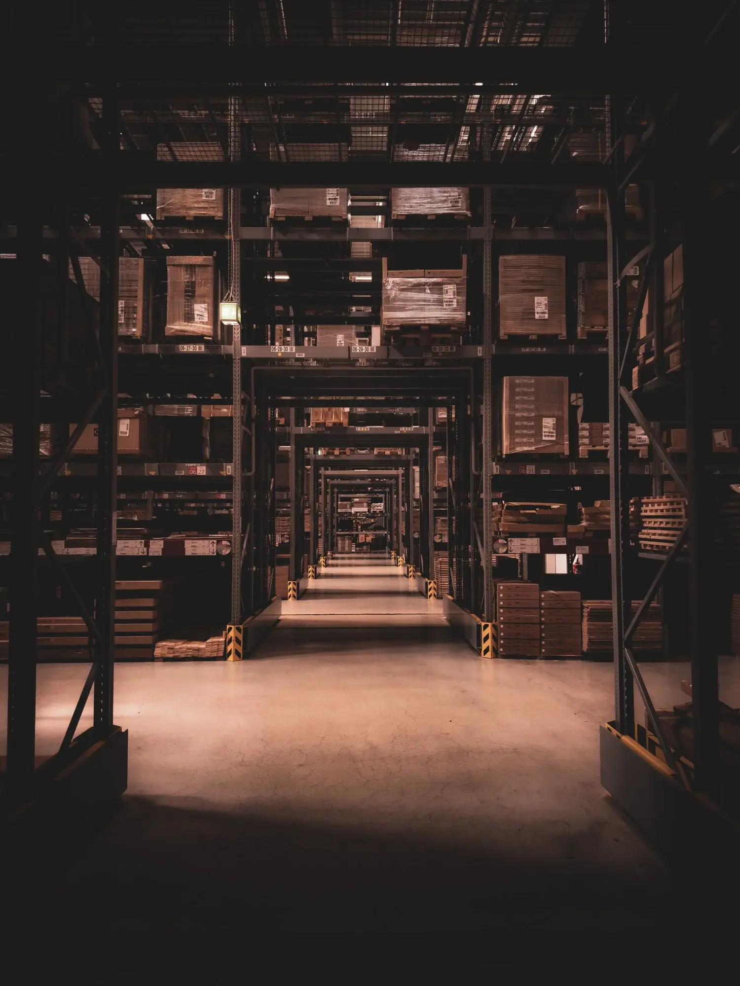 Deep aisle inside a UK pallet-storage warehouse with high racking on both sides