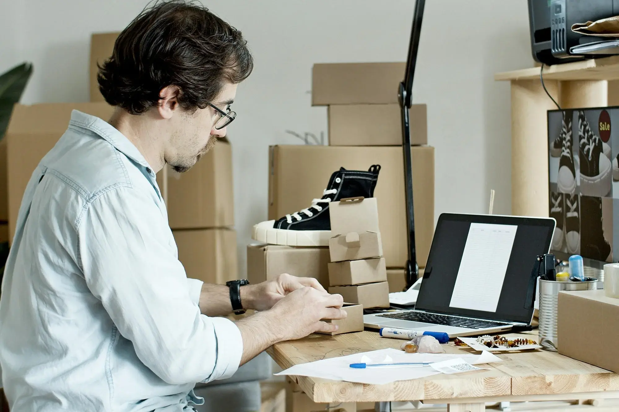 Small-business founder packing orders at a kitchen-table workspace